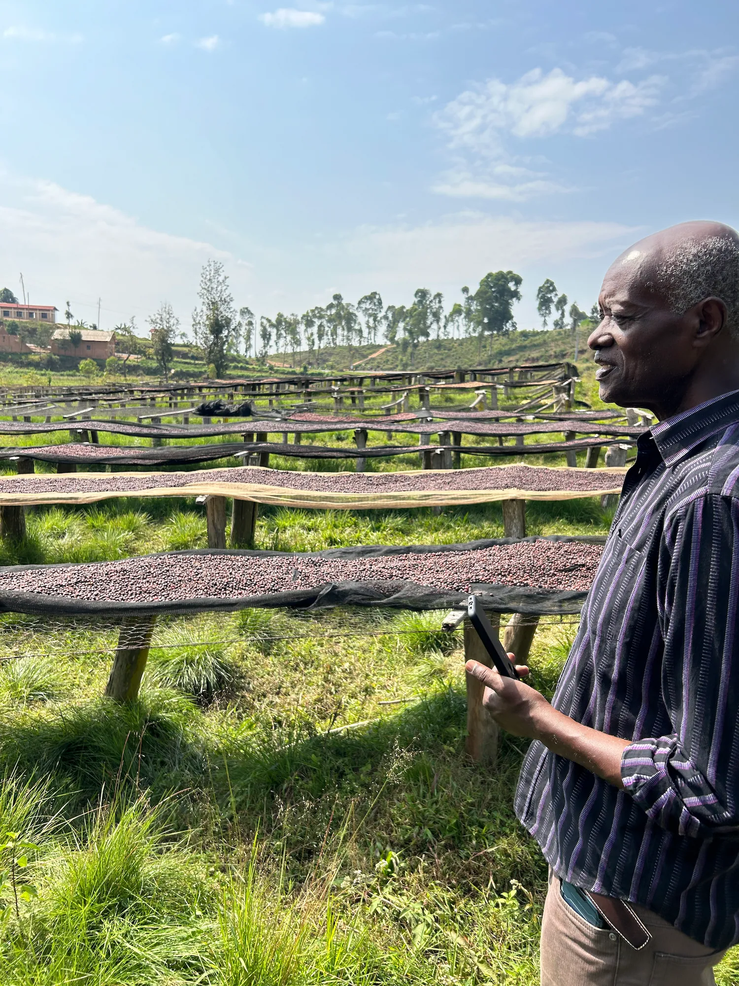 ブルンジ共和国のコーヒー生産者エフレムさんが精製所で乾燥しているコーヒーチェリーの前で話している様子